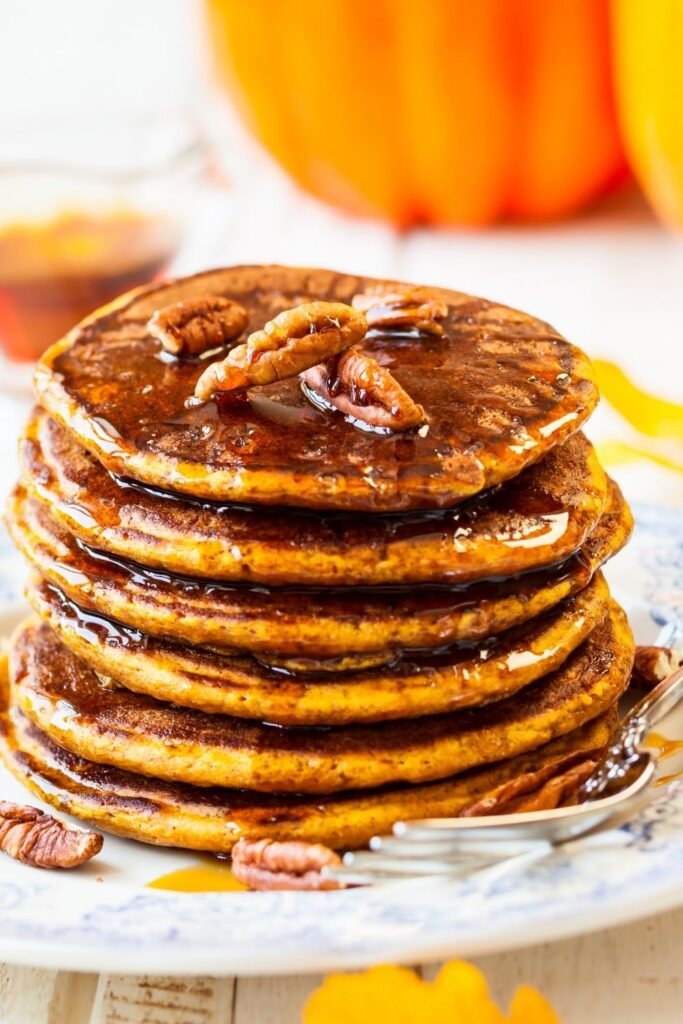 Stack of pumpkin pancakes with syrup and pecans
